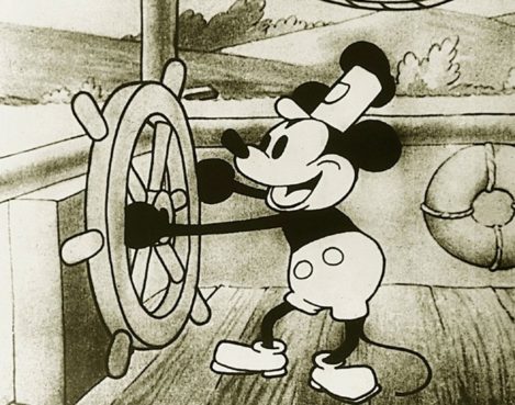 Mickey Mouse holding a wheel on a boat; this black-and-white image from the film Steamboat Willie is an example of works entering public domain.